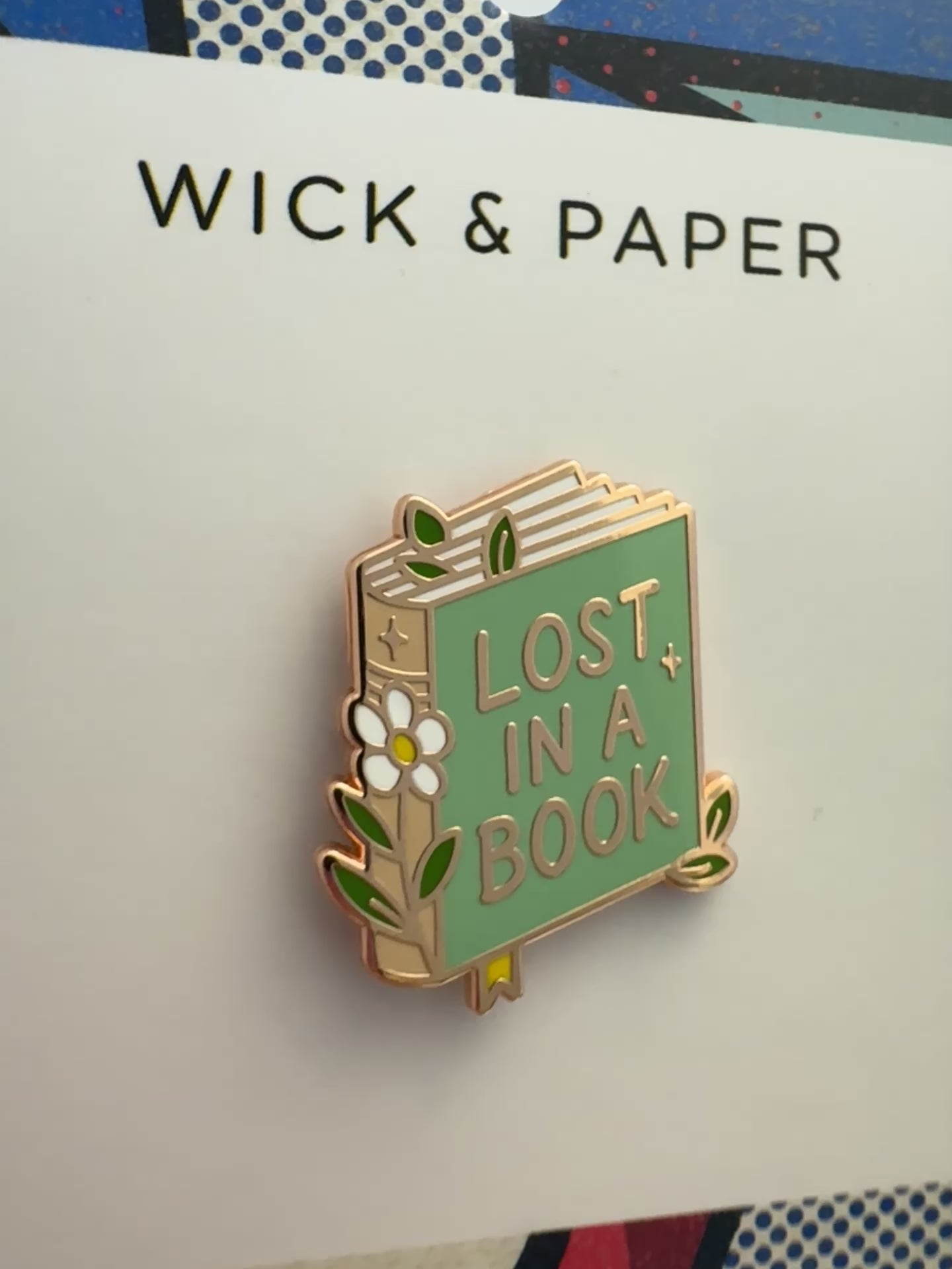 Book-themed enamel pin reading “Lost in a Book,” by Wick and Paper.